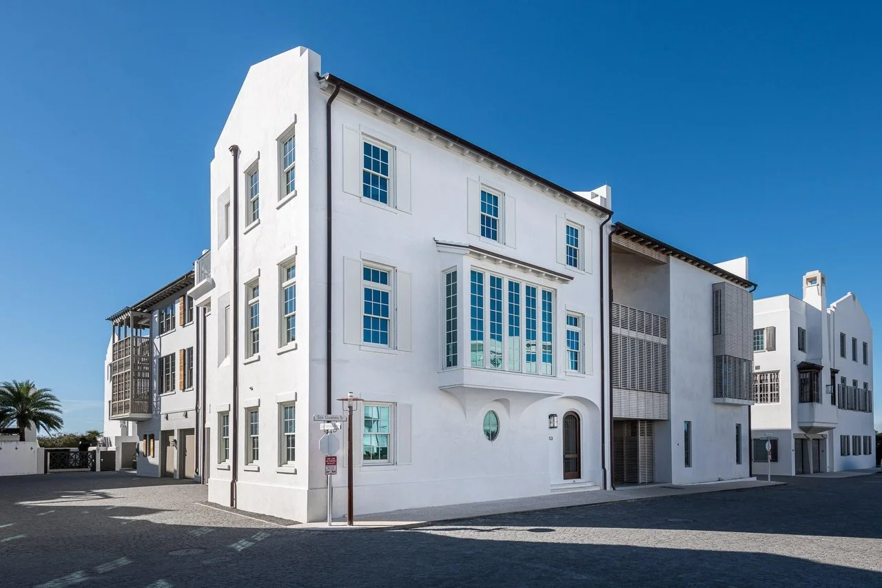White multi-story building with large windows and modern architectural design, under a clear blue sky.