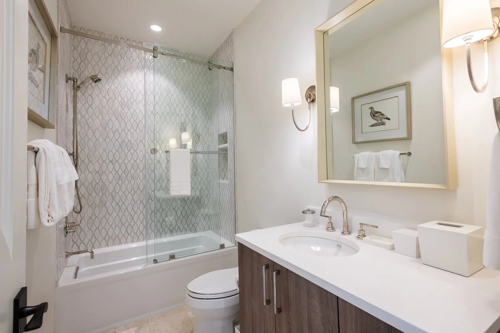 Modern bathroom with a bathtub and shower, white countertop, large mirror, and framed artwork, decorated in neutral tones.