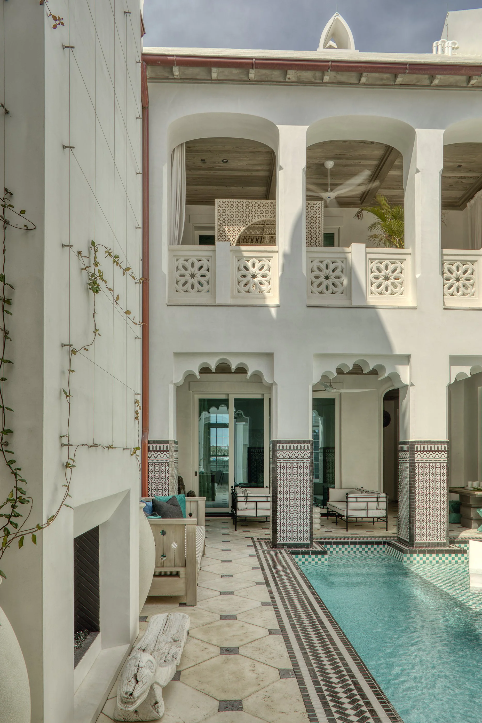 A luxurious indoor pool area with white walls, patterned tiles, and lounge chairs.